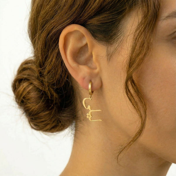 Personalized name drop earrings in Arabic in gold finish worn on ear, side profile view