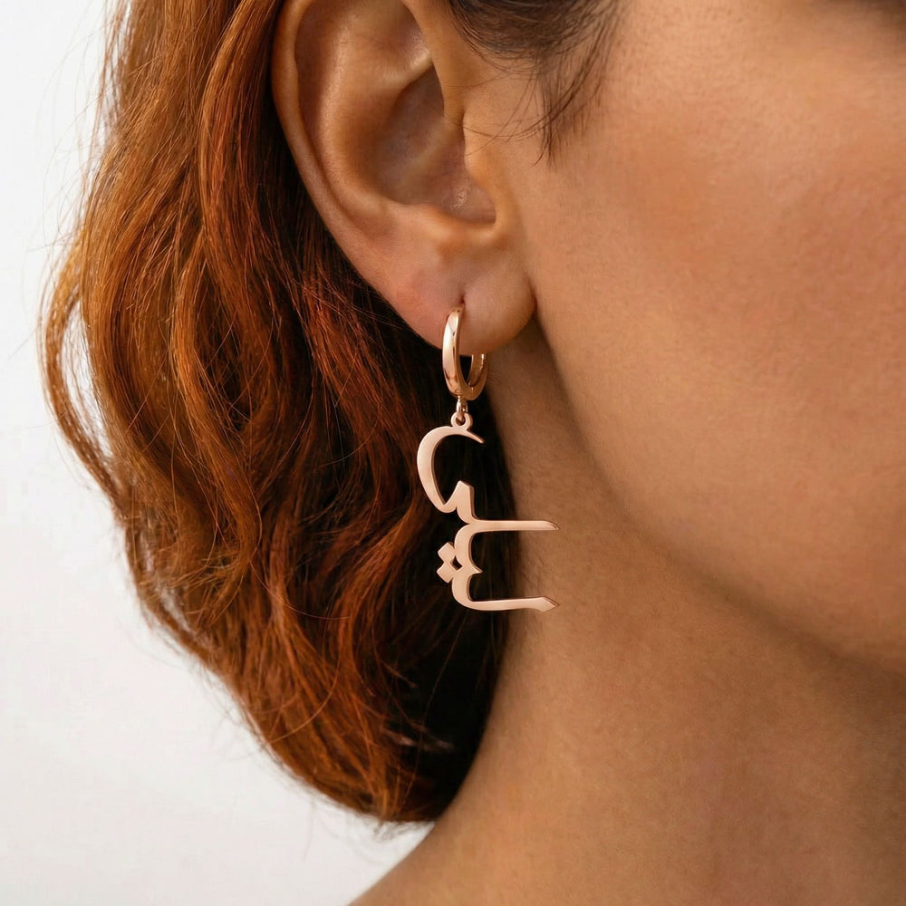 Personalized name drop earrings in Arabic in rose gold finish worn on ear, side profile view