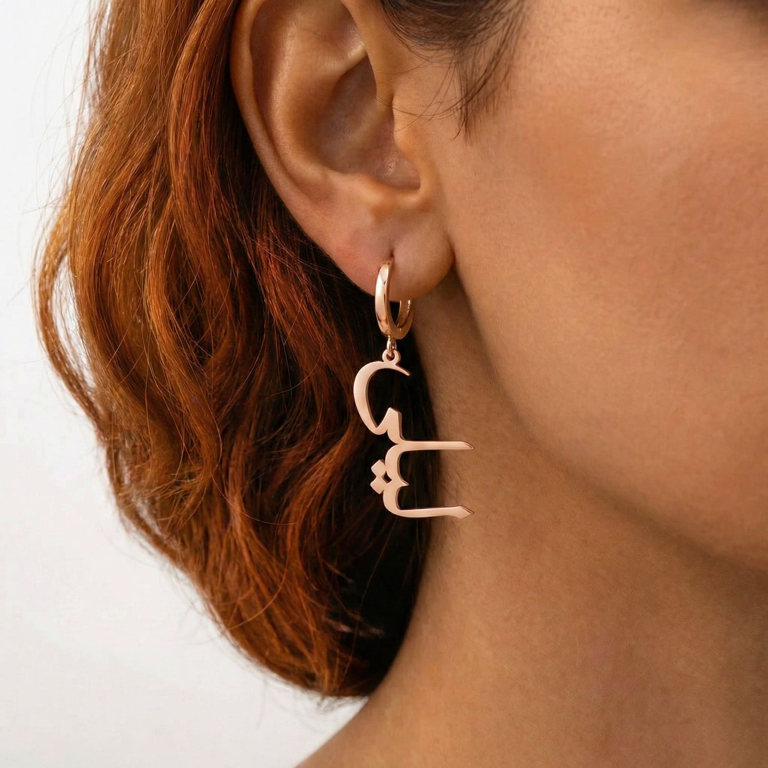 Personalized name drop earrings in Arabic in rose gold finish worn on ear, side profile view
