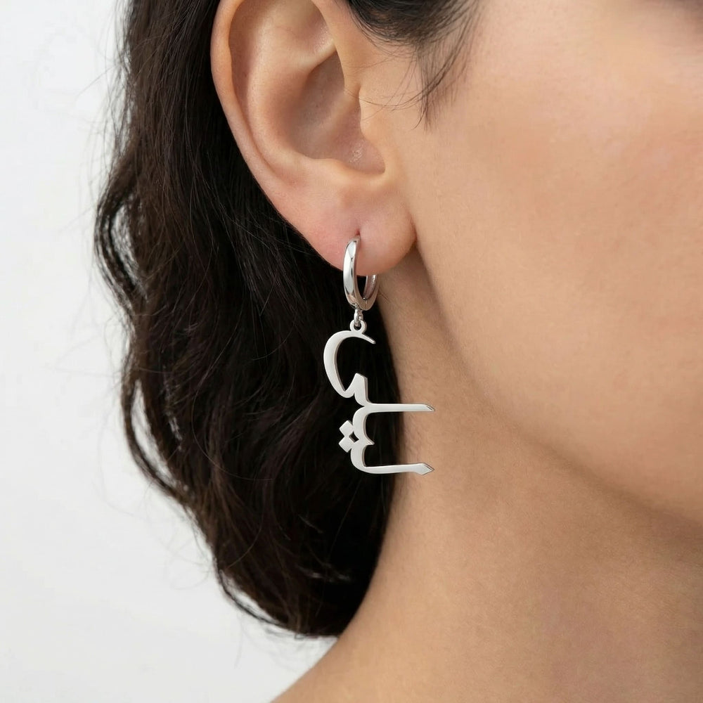 Personalized name drop earrings in Arabic in silver finish worn on ear, side profile view