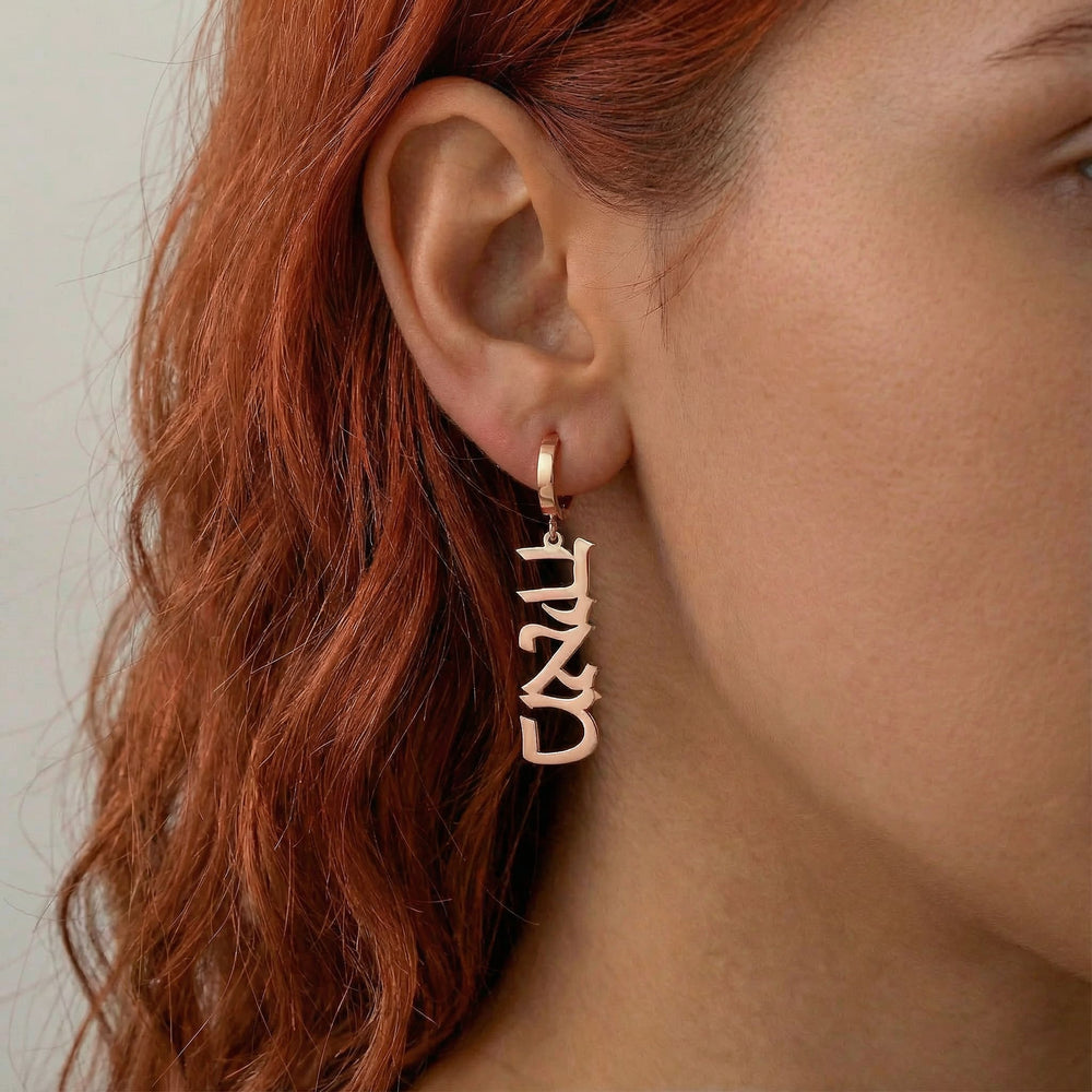 Personalized name drop earrings in Hebrew in rose gold finish worn on ear, side profile view