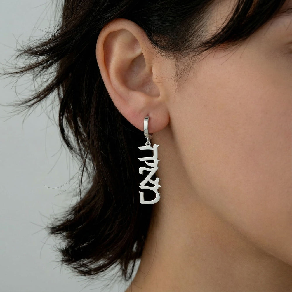 Personalized name drop earrings in Hebrew in silver finish worn on ear, side profile view
