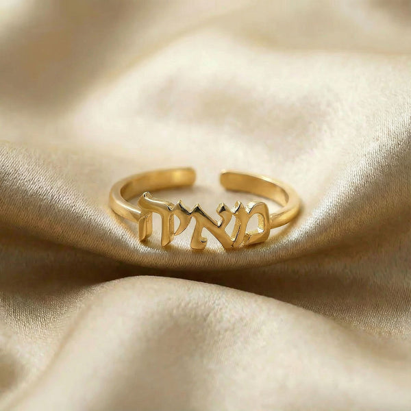 Personalized name ring in Hebrew, one-size in gold finish on beige silk fabric