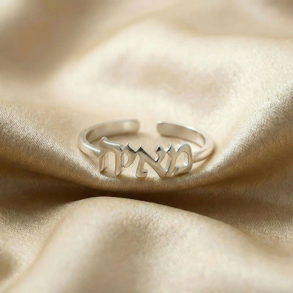 Personalized name ring in Hebrew, one-size in silver finish on beige silk fabric