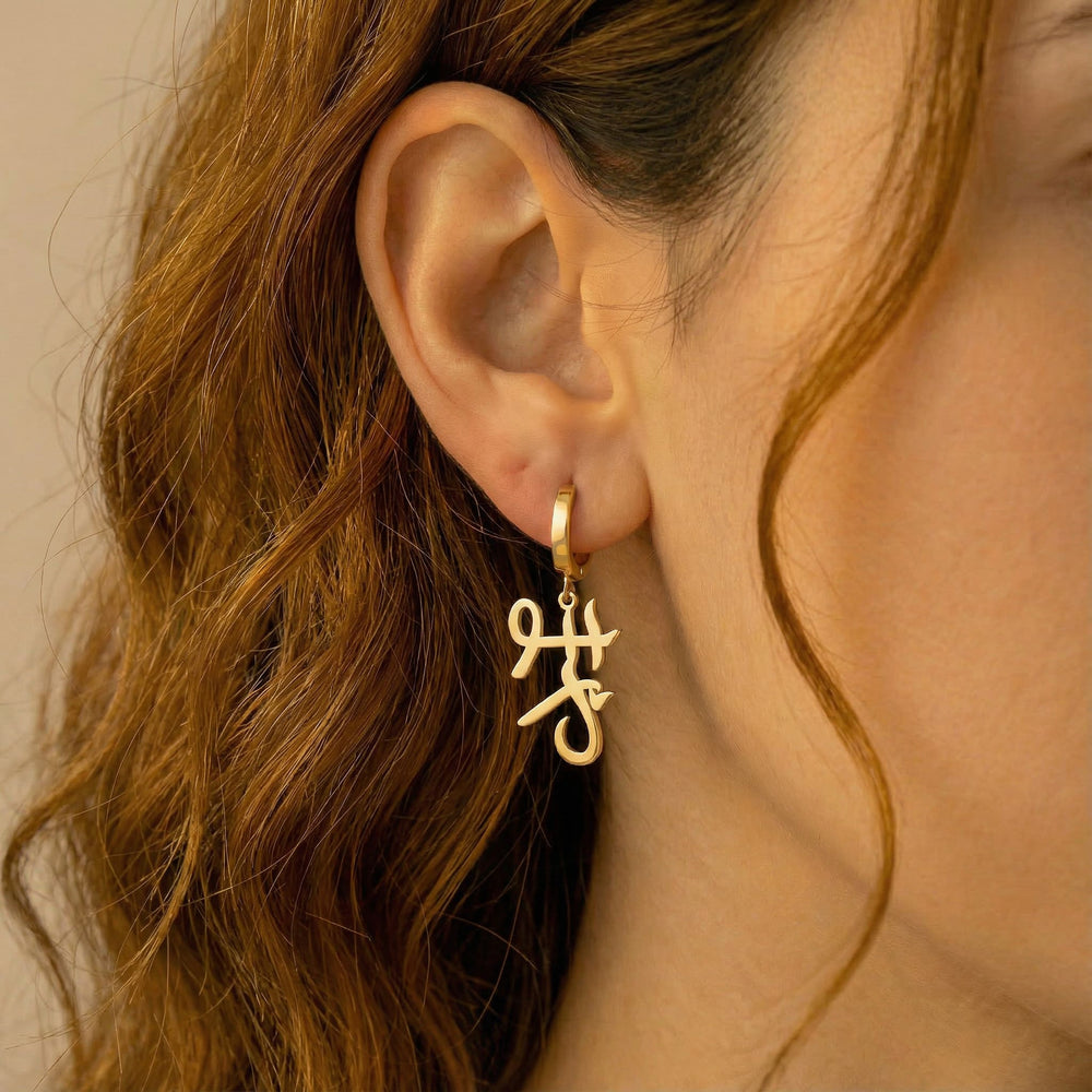 Personalized name drop earrings in Japanese in gold finish worn on ear, side profile view
