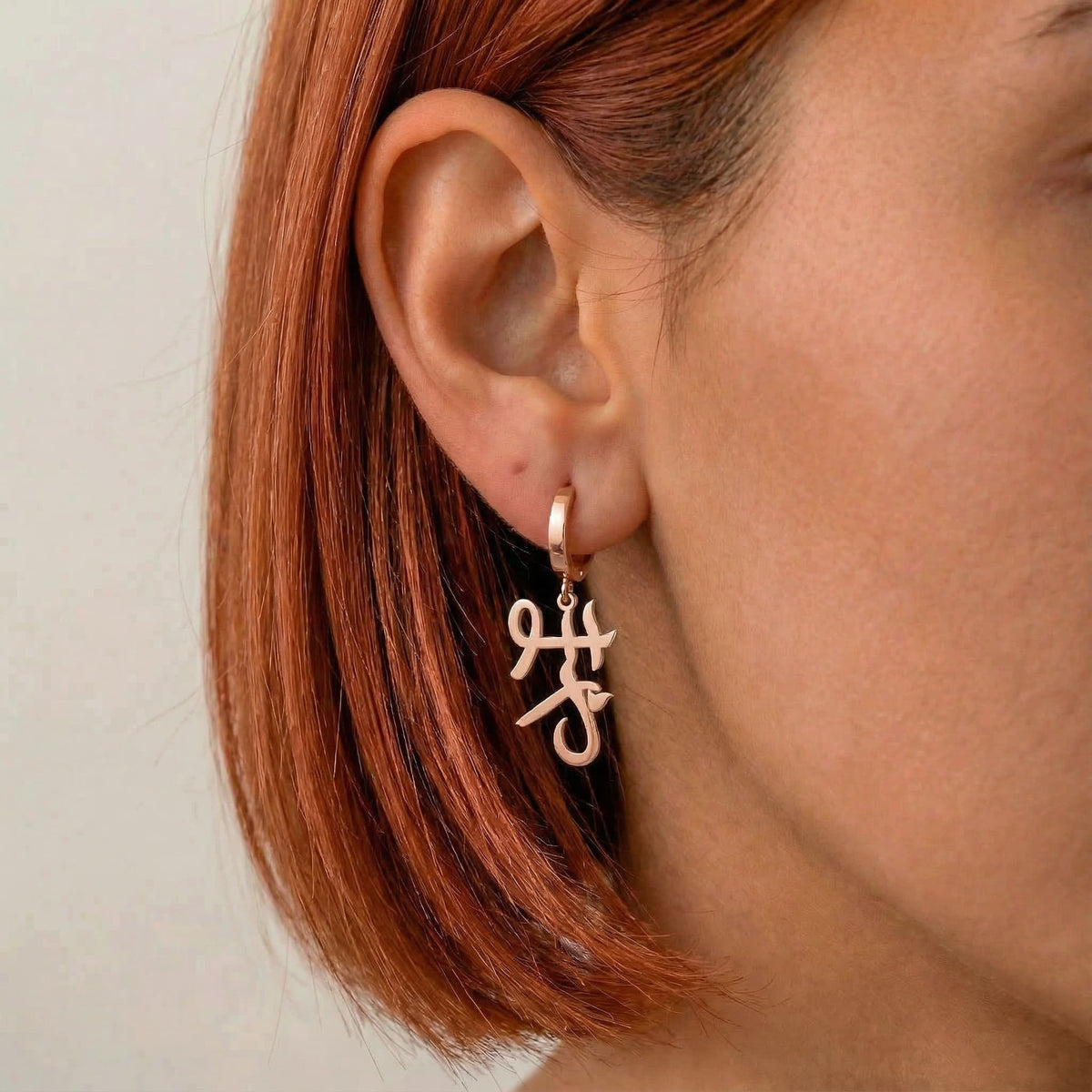 Personalized name drop earrings in Japanese in rose gold finish worn on ear, side profile view