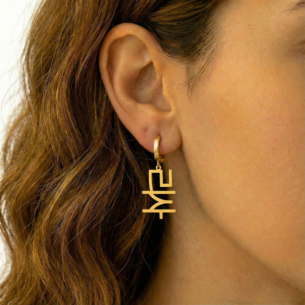 Personalized name drop earrings in Korean in gold finish worn on ear, side profile view