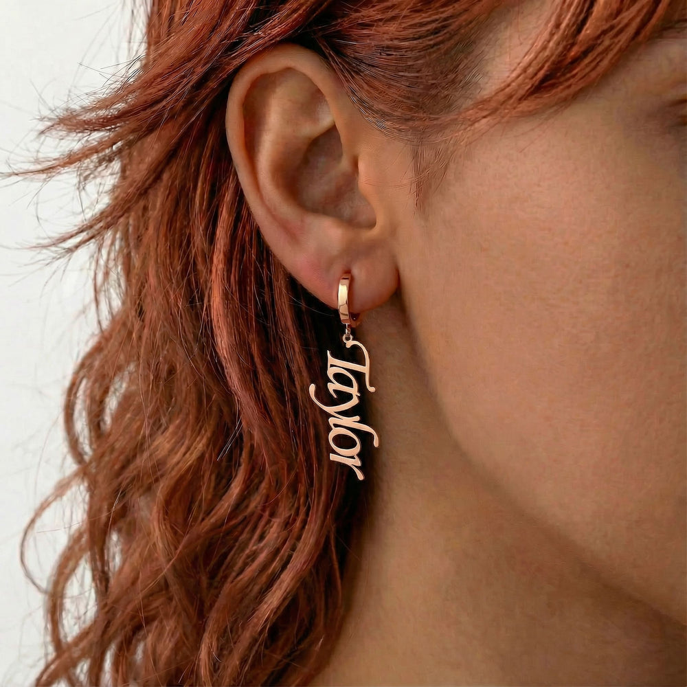 Personalized name drop earrings in rose gold finish worn on ear, side profile view