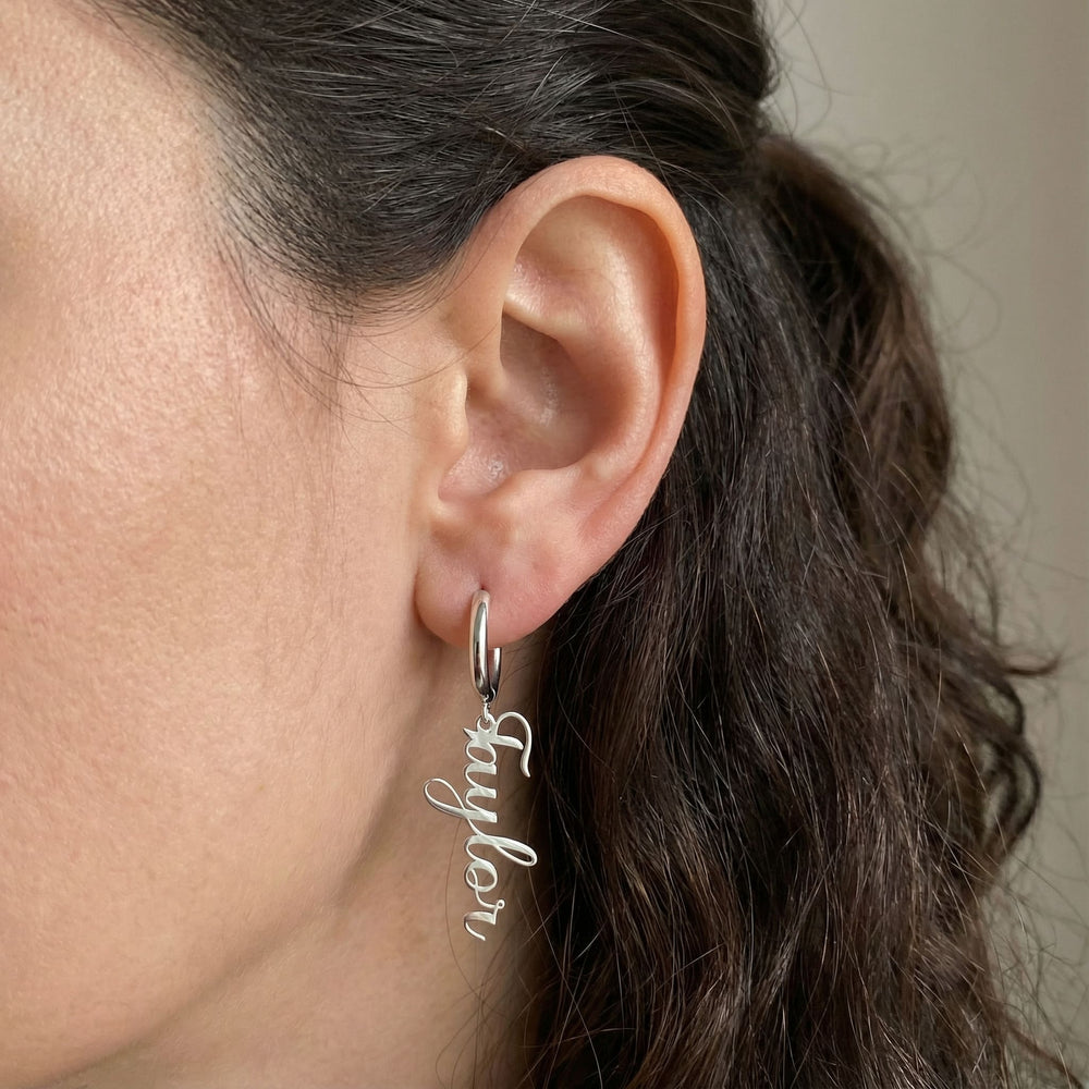 Personalized name drop earrings in silver finish worn on ear, side profile view
