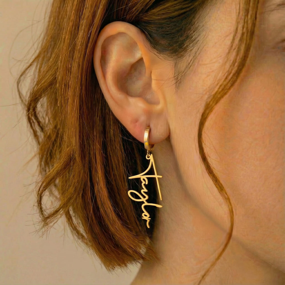 Personalized name drop earrings in gold finish worn on ear, side profile view