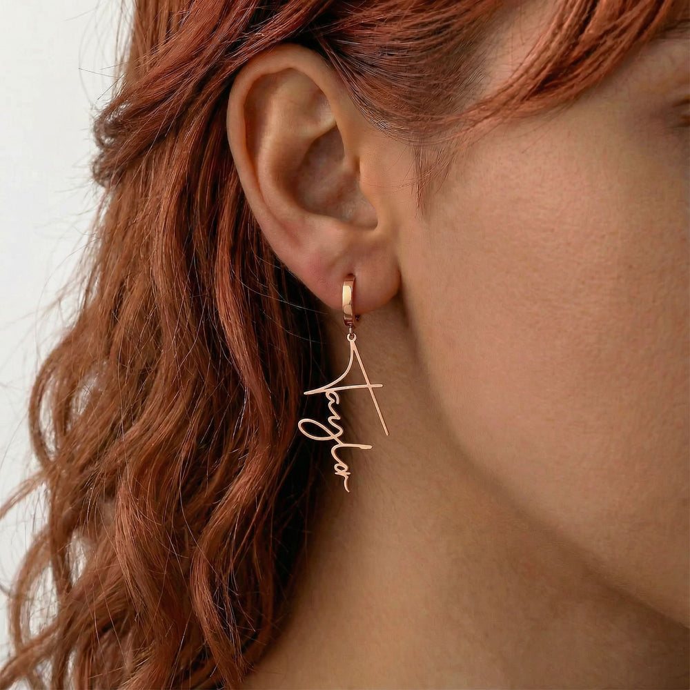 Personalized name drop earrings in rose gold finish worn on ear, side profile view