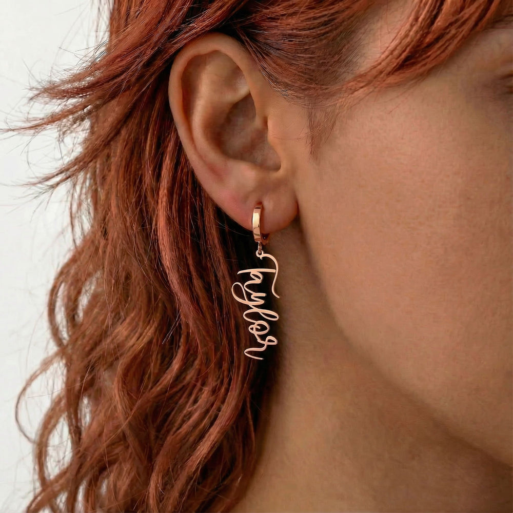 Personalized name drop earrings in rose gold finish worn on ear, side profile view
