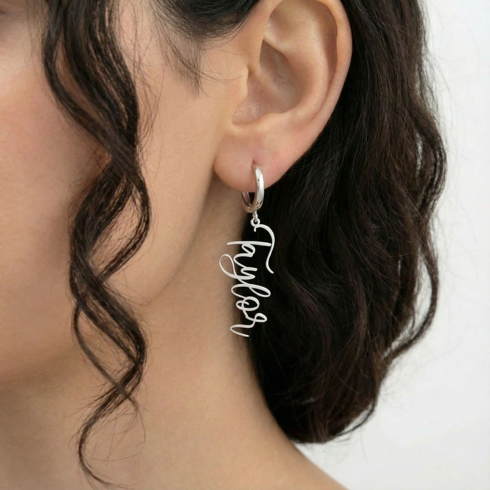 Personalized name drop earrings in silver finish worn on ear, side profile view