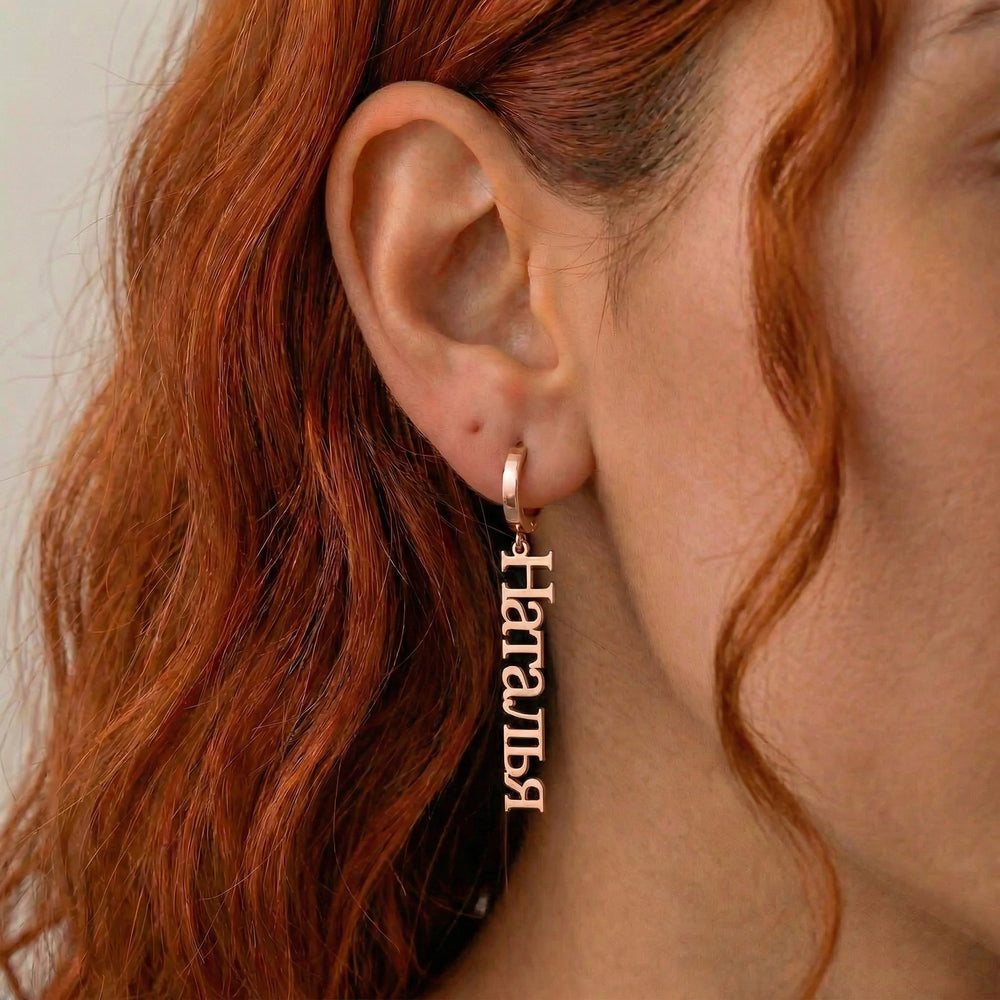 Personalized name drop earrings in Cyrillic in rose gold finish worn on ear, side profile view