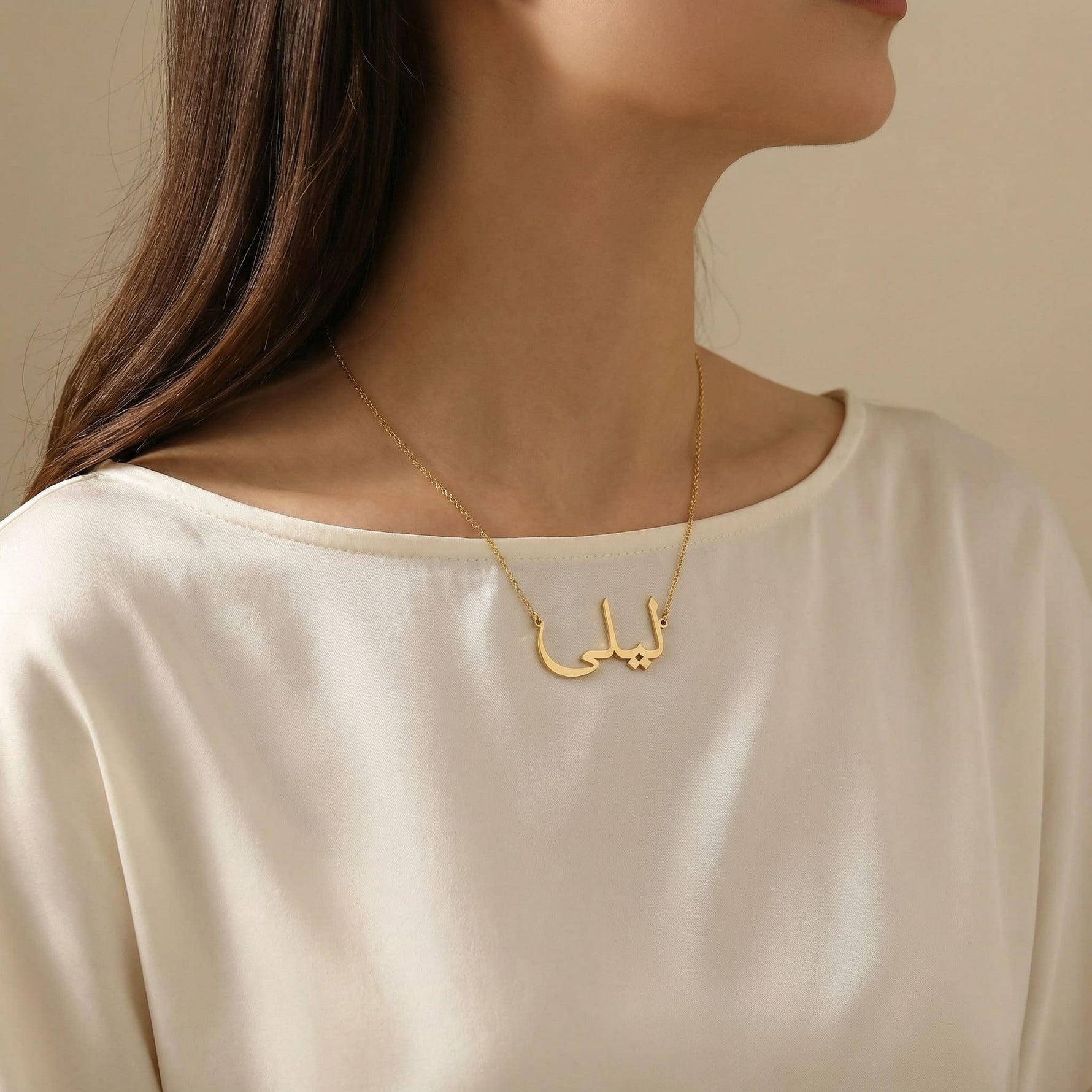 Gold Arabic script name necklace reading ليلى worn on woman’s neck in lifestyle photo