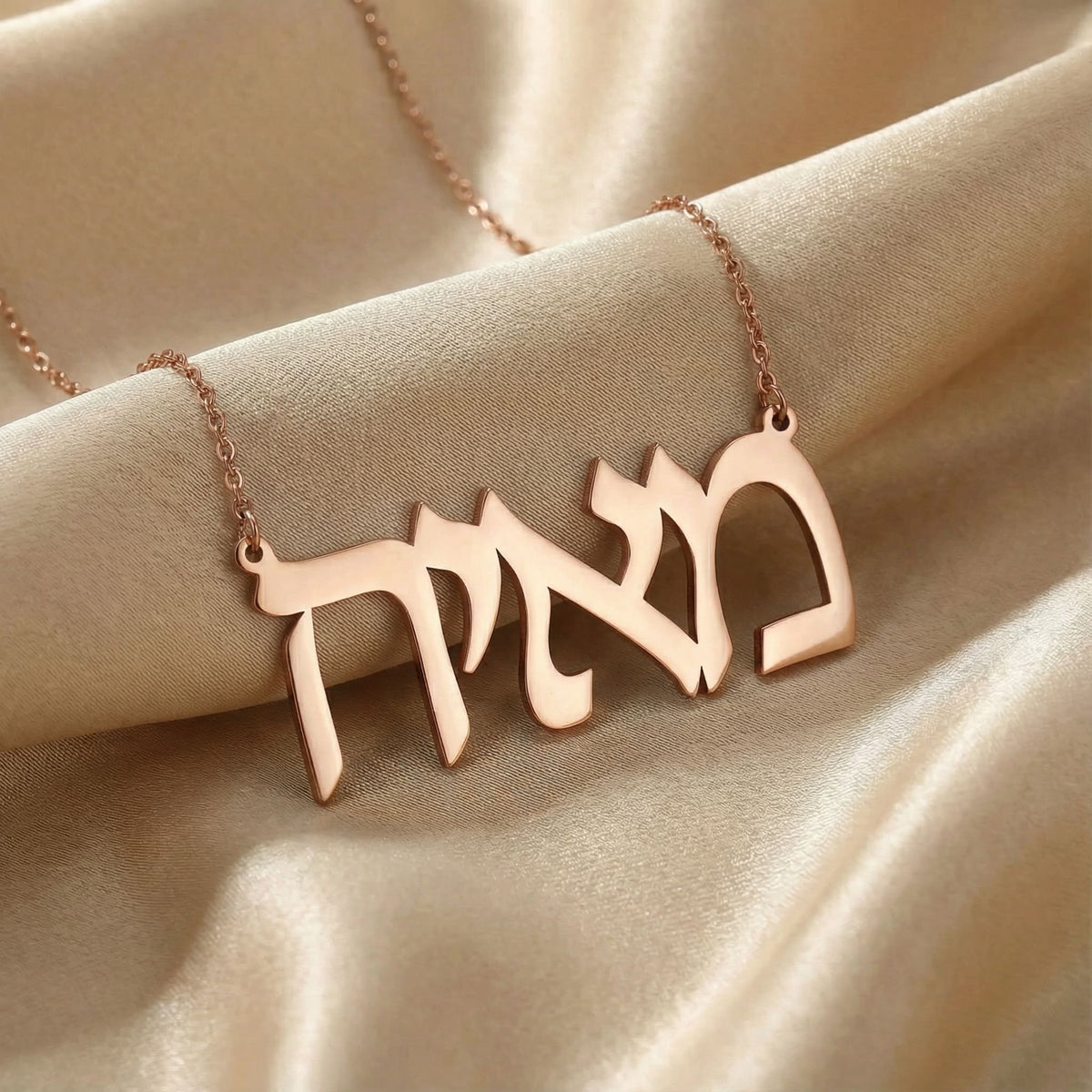 Personalized name necklace in Hebrew in rose gold finish on beige silk fabric