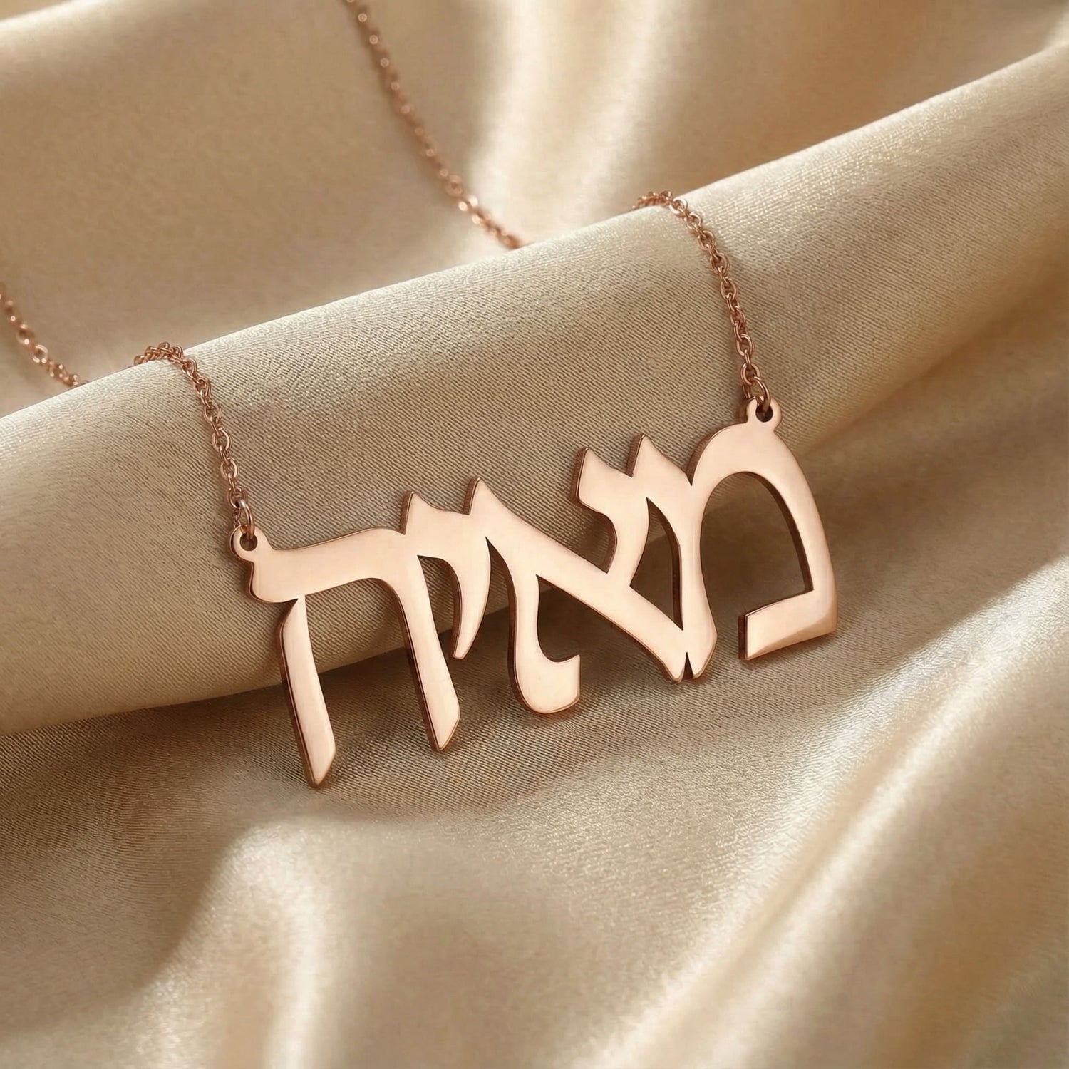 Personalized name necklace in Hebrew in rose gold finish on beige silk fabric
