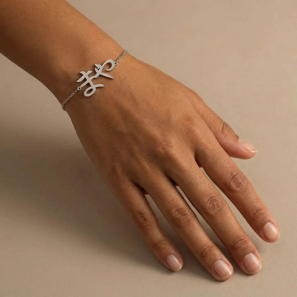 Silver Japanese Katakana name bracelet worn on a medium toned hand with short natural nails, photographed on a soft beige background with a calm minimal look.