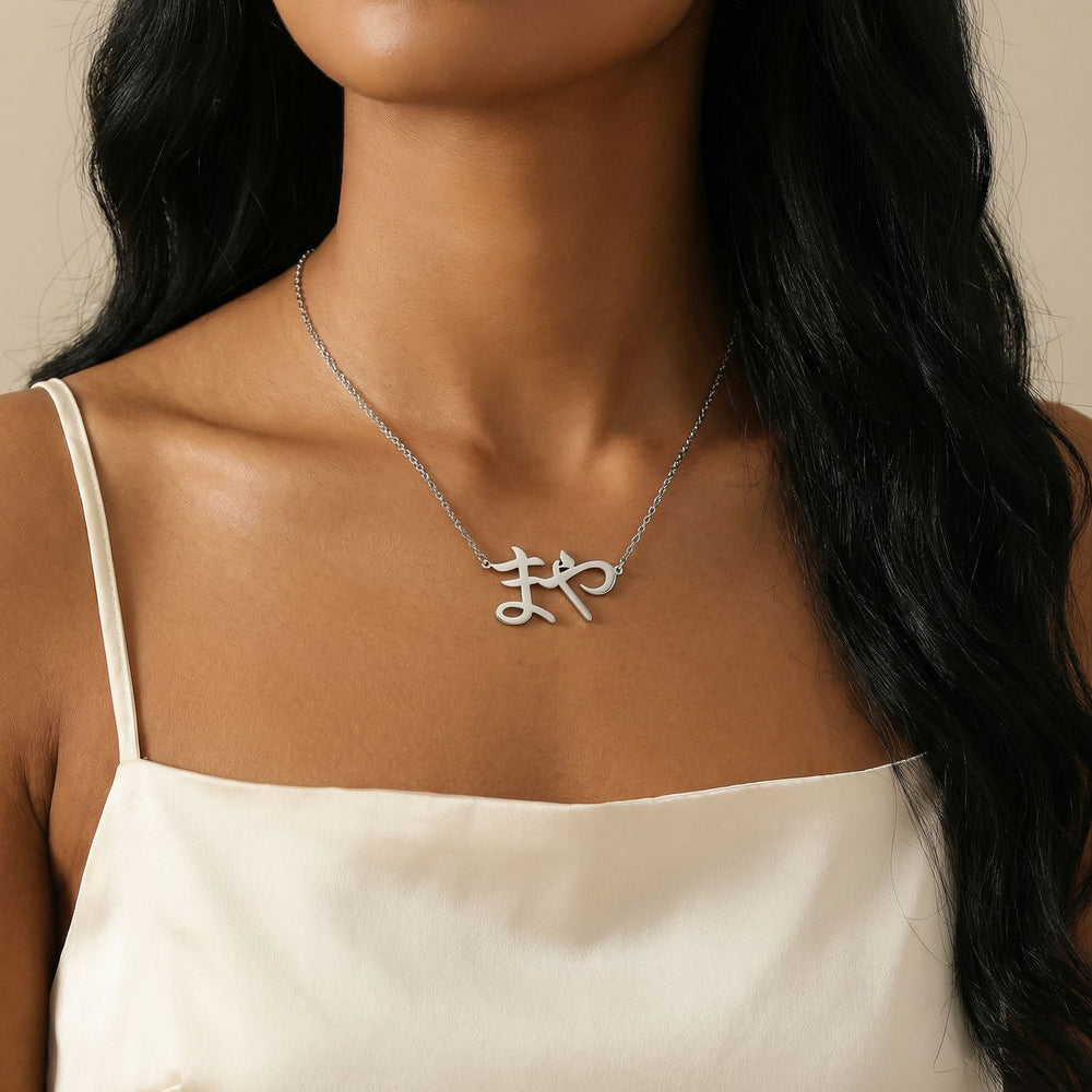 Silver Japanese script name necklace reading まや worn on woman’s neck in lifestyle shot