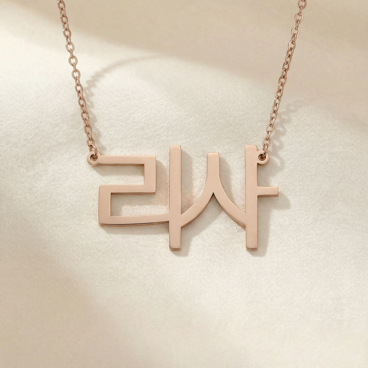 Personalized name necklace in Korean in rose gold finish on beige silk fabric