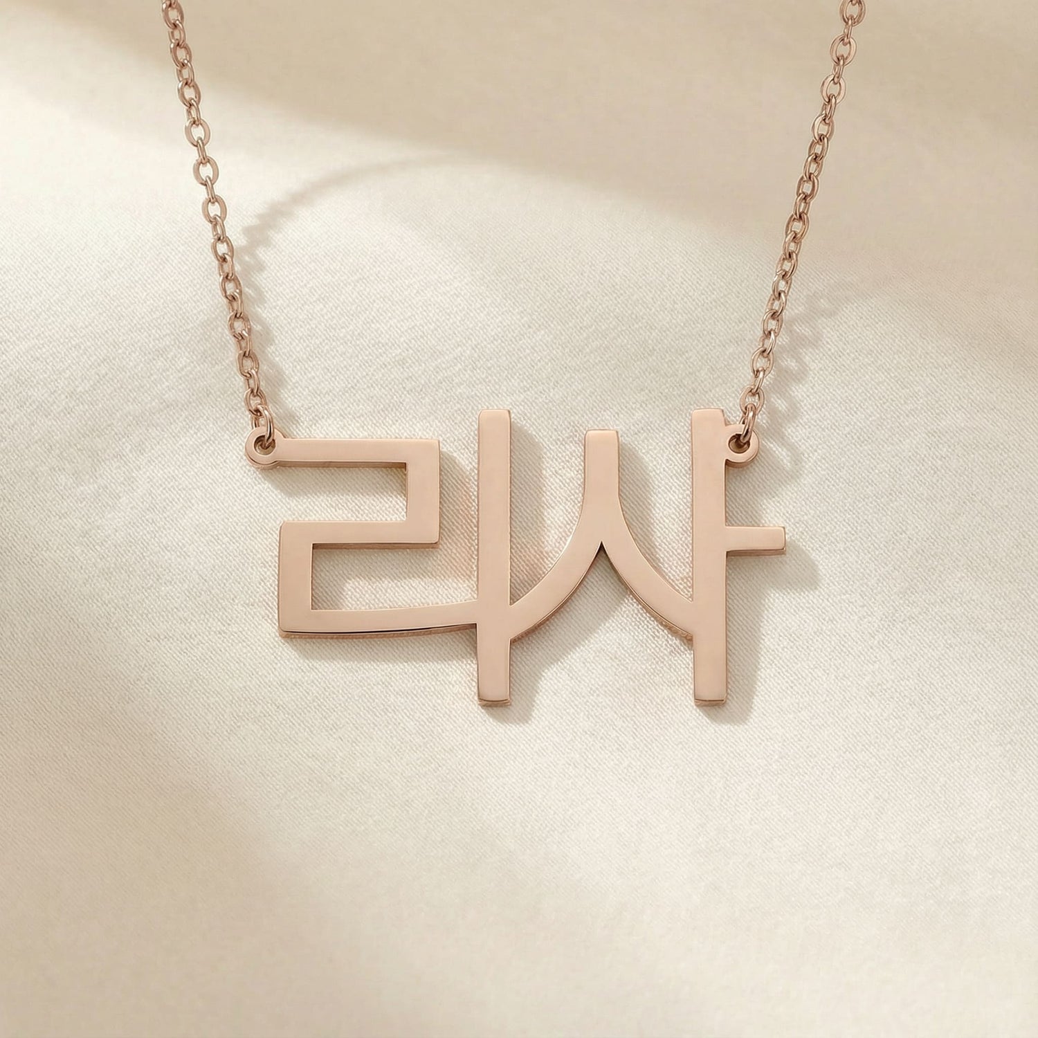 Personalized name necklace in Korean in rose gold finish on beige silk fabric