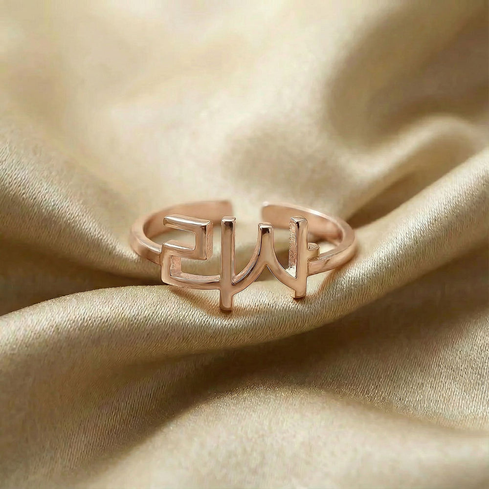 Personalized name ring in Korean, one-size in rose gold finish on beige silk fabric