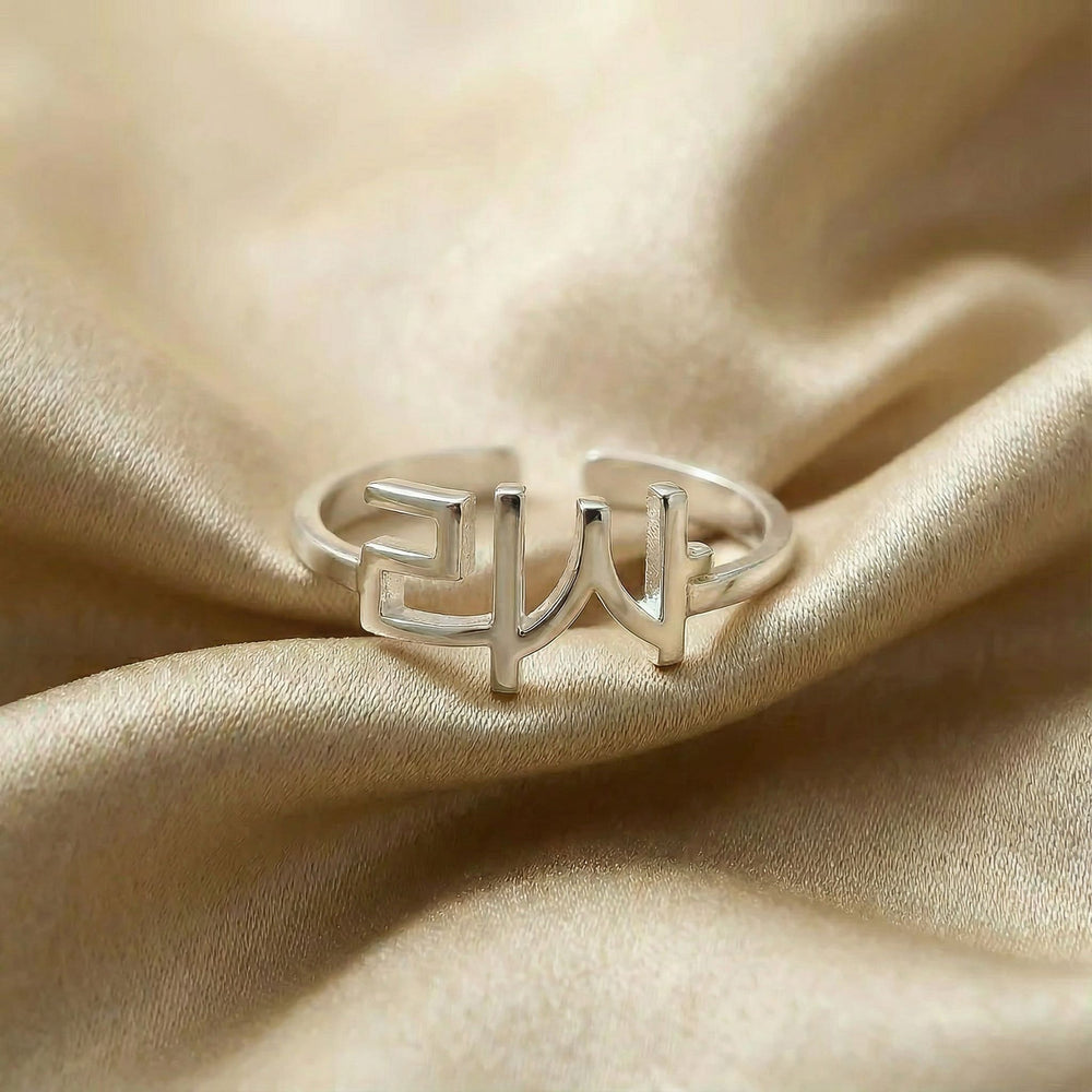 Personalized name ring in Korean, one-size in silver finish on beige silk fabric