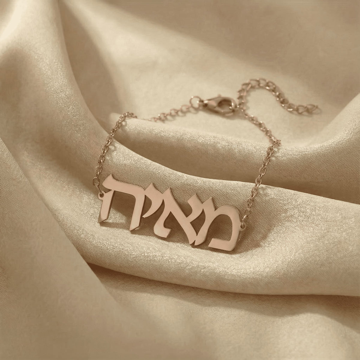 Personalized name bracelet in Hebrew in rose gold finish on beige silk fabric