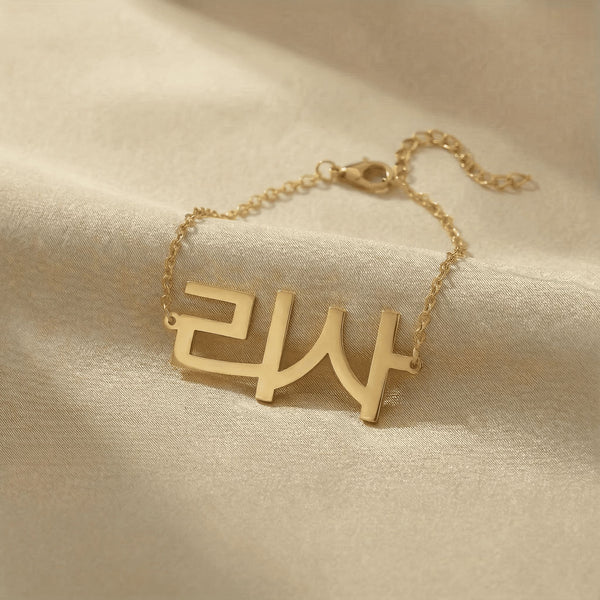 Personalized name bracelet in Korean in gold finish on beige silk fabric