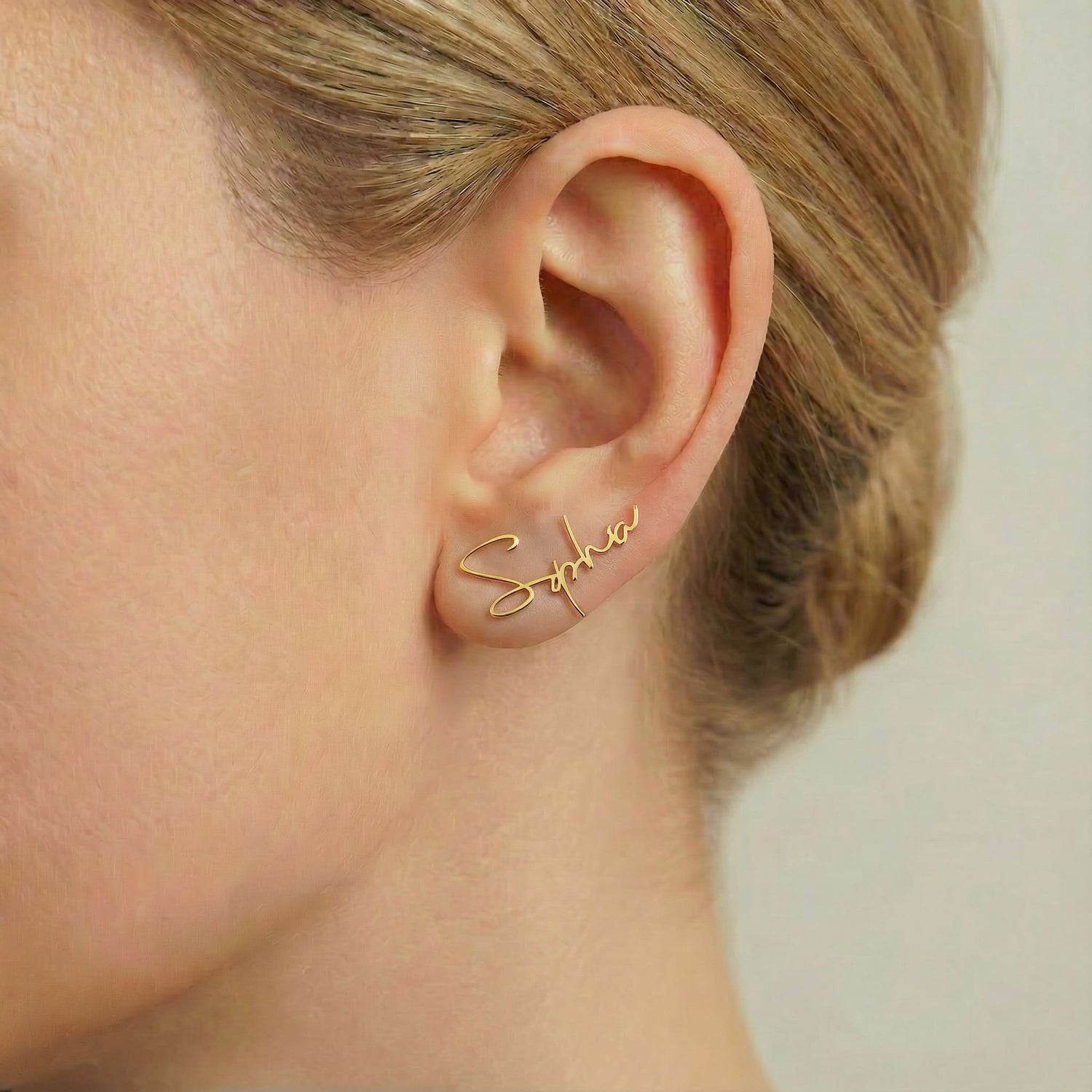 Personalized name ear climber earrings in gold finish worn on ear, side profile view
