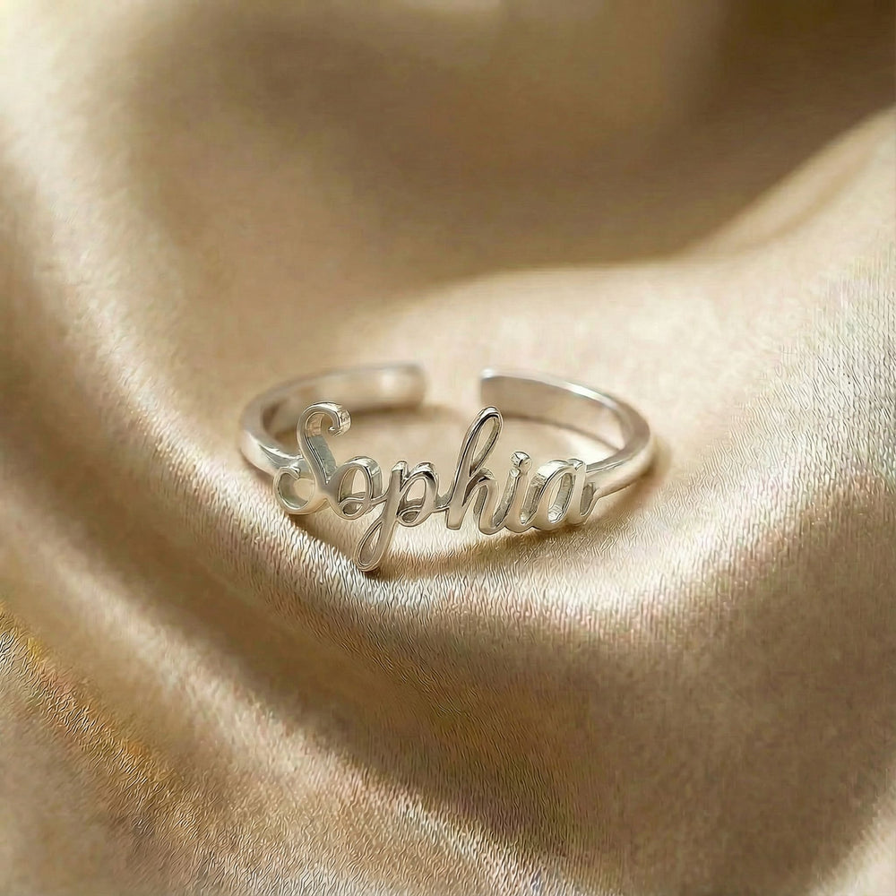 Personalized name ring, one-size in silver finish on beige silk fabric