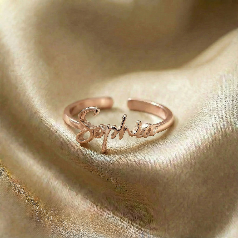 Personalized name ring, one-size in rose gold finish on beige silk fabric