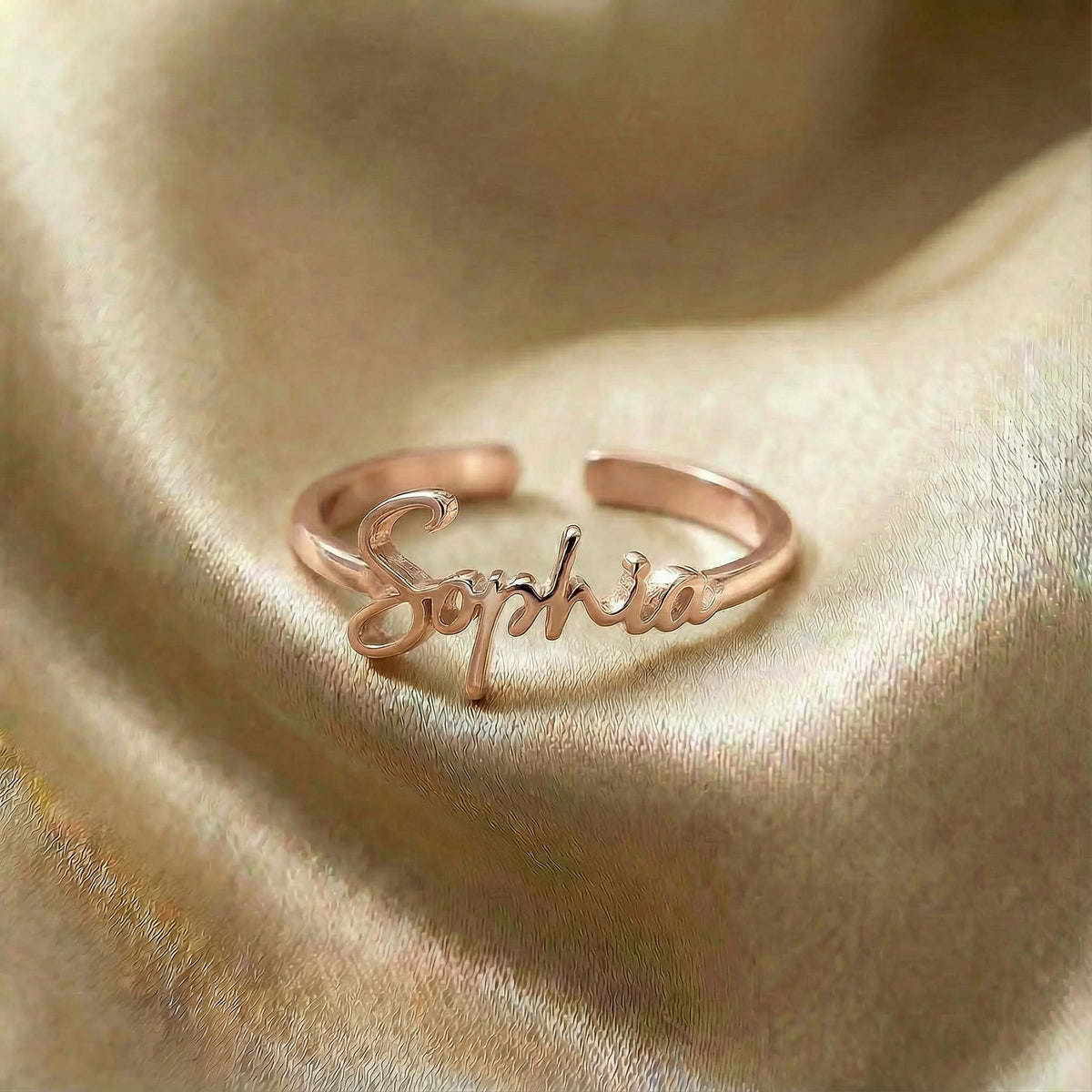 Personalized name ring, one-size in rose gold finish on beige silk fabric