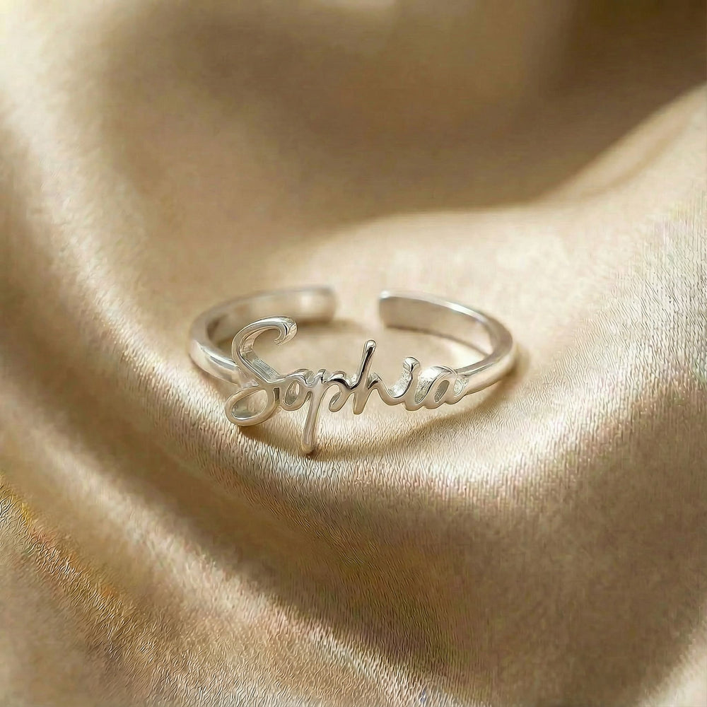 Personalized name ring, one-size in silver finish on beige silk fabric