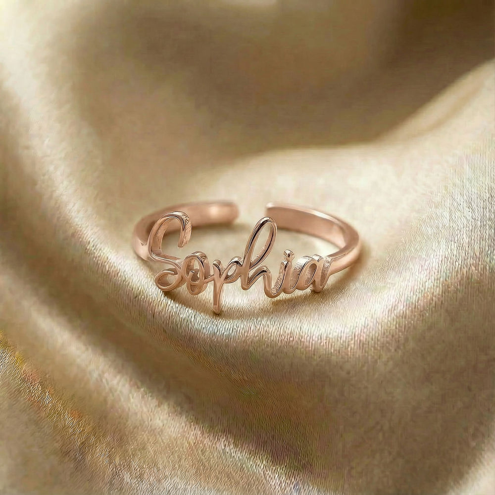 Personalized name ring, one-size in rose gold finish on beige silk fabric