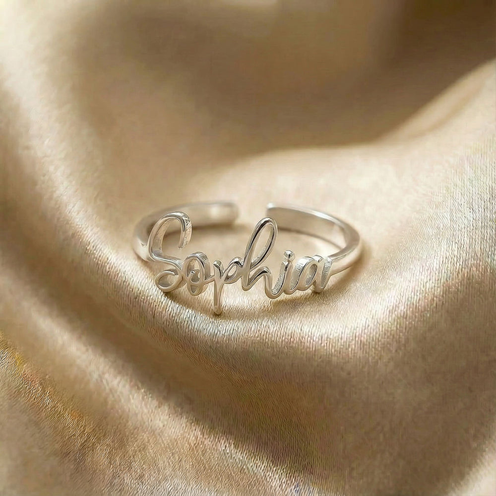 Personalized name ring, one-size in silver finish on beige silk fabric