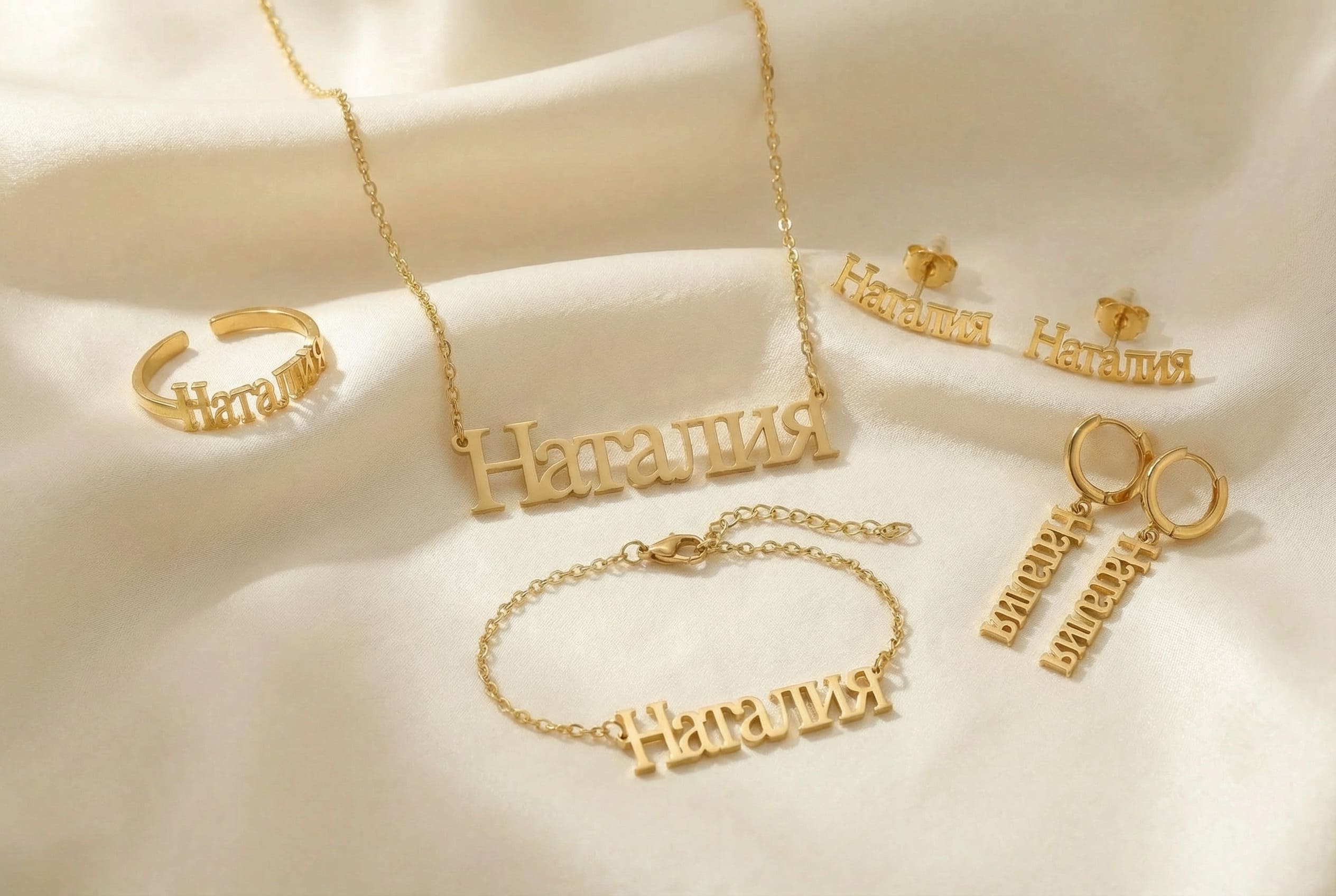 Gold russian name jewelry set including necklace, ring, bracelet, and earrings on a silk light cloth