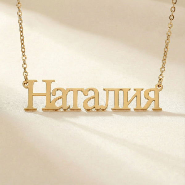 Personalized name necklace in Cyrillic in gold finish on beige silk fabric