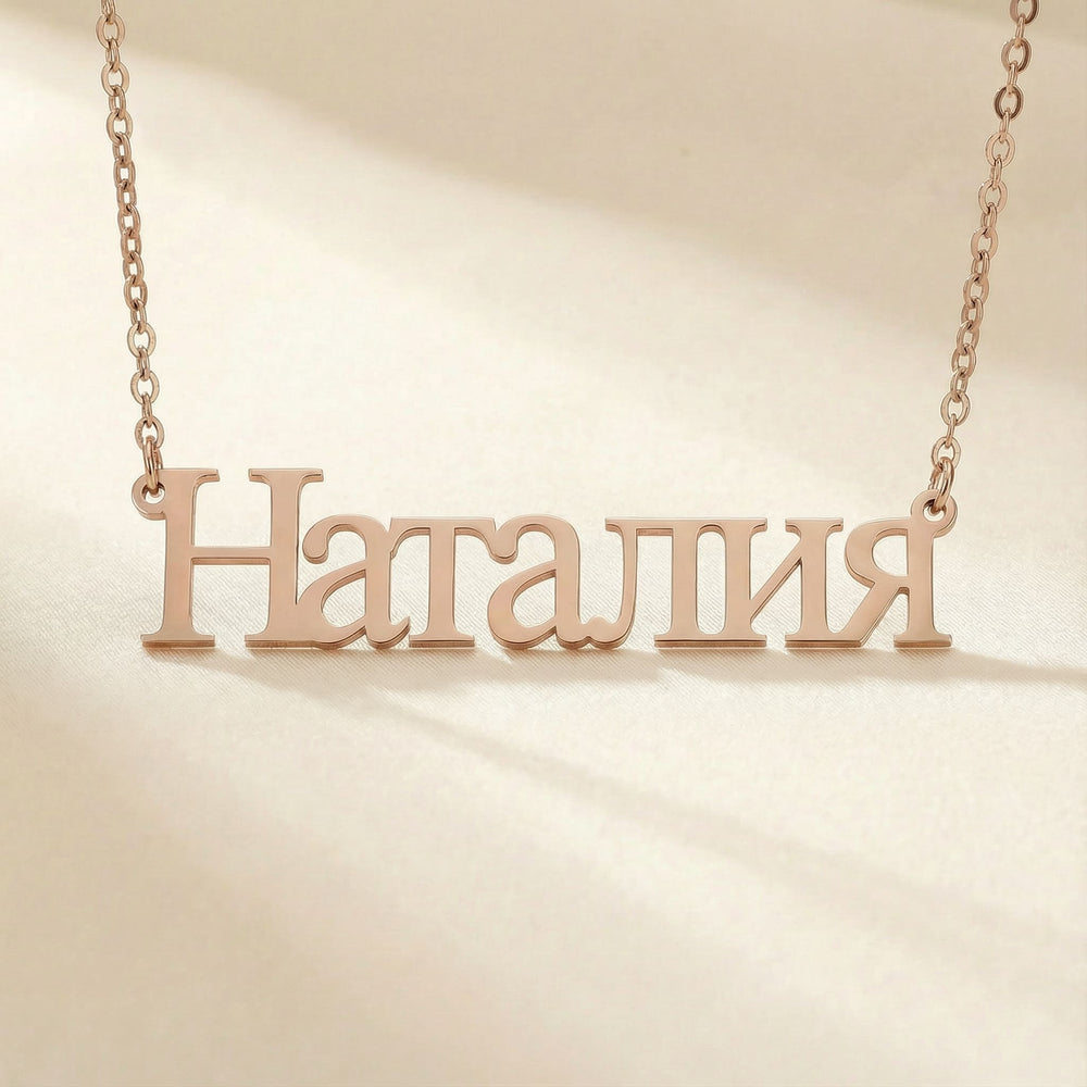 Personalized name necklace in Cyrillic in rose gold finish on beige silk fabric