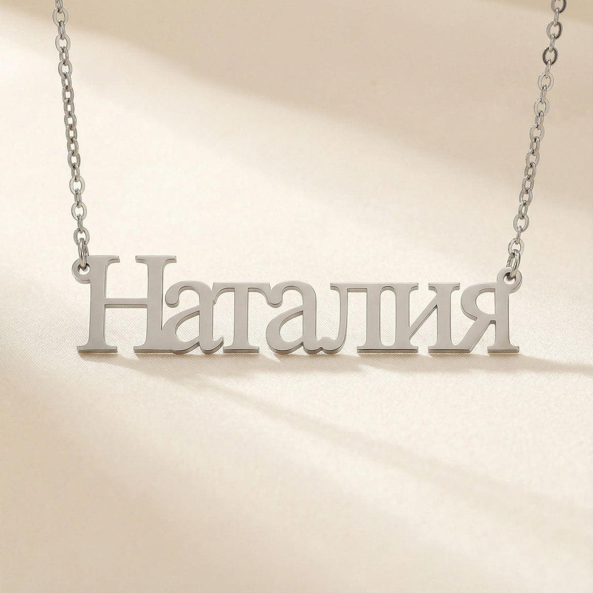 Personalized name necklace in Cyrillic in silver finish on beige silk fabric
