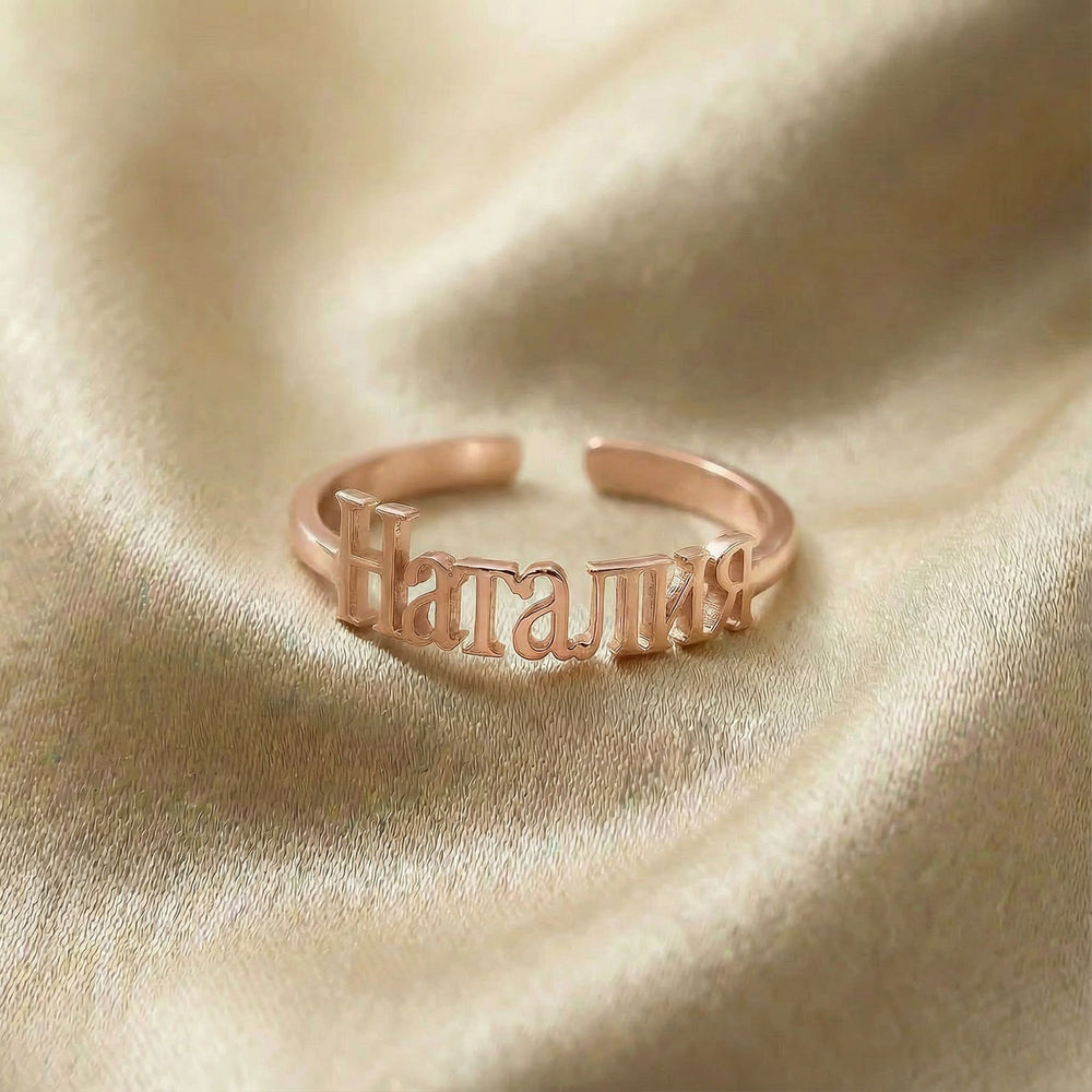 Personalized name ring in Cyrillic, one-size in rose gold finish on beige silk fabric