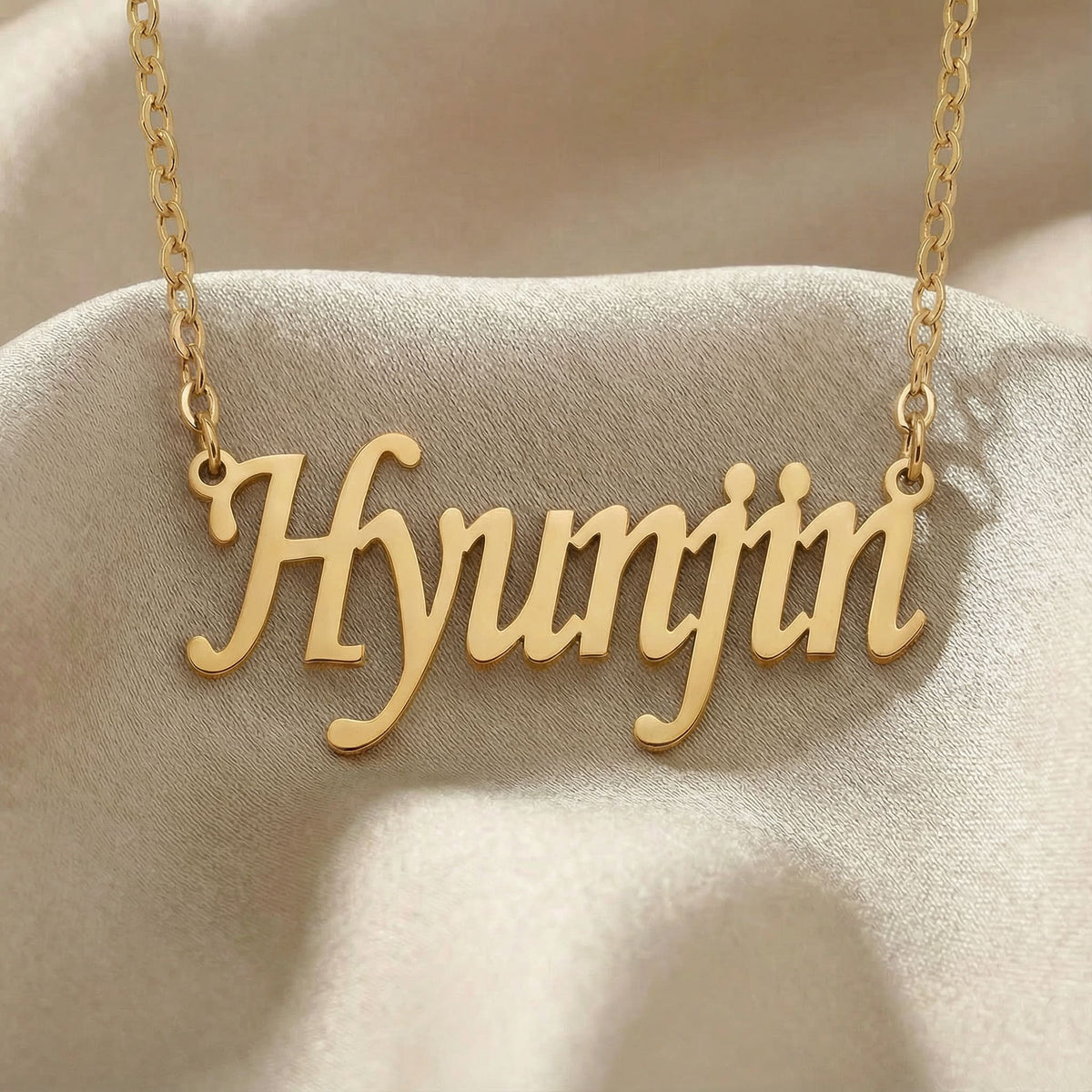 Personalized name necklace in gold finish on beige silk fabric