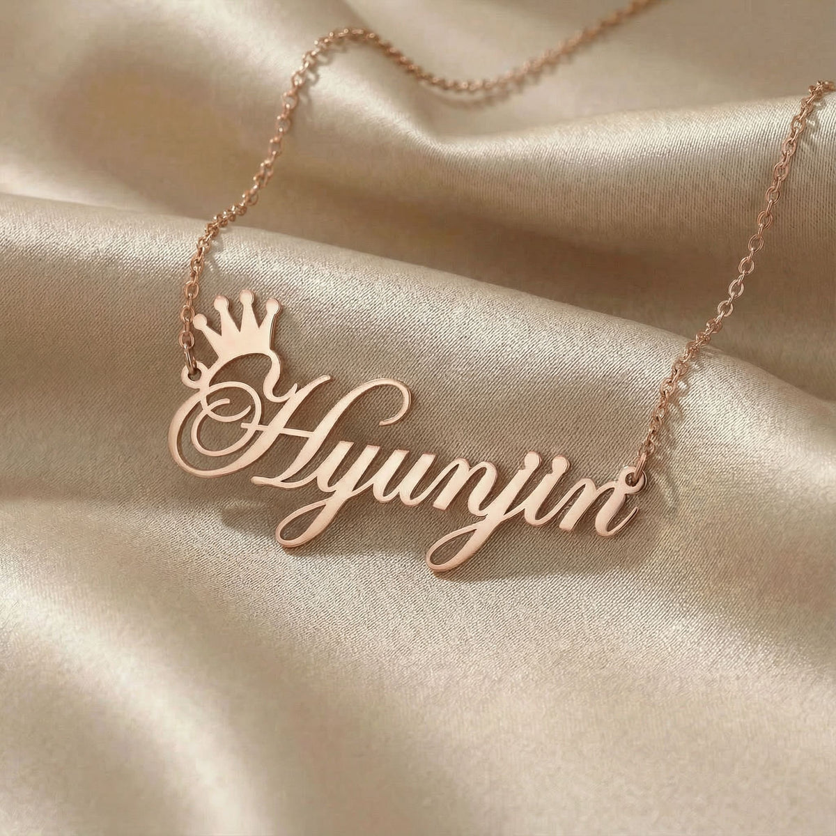 Personalized name necklace in rose gold finish on beige silk fabric
