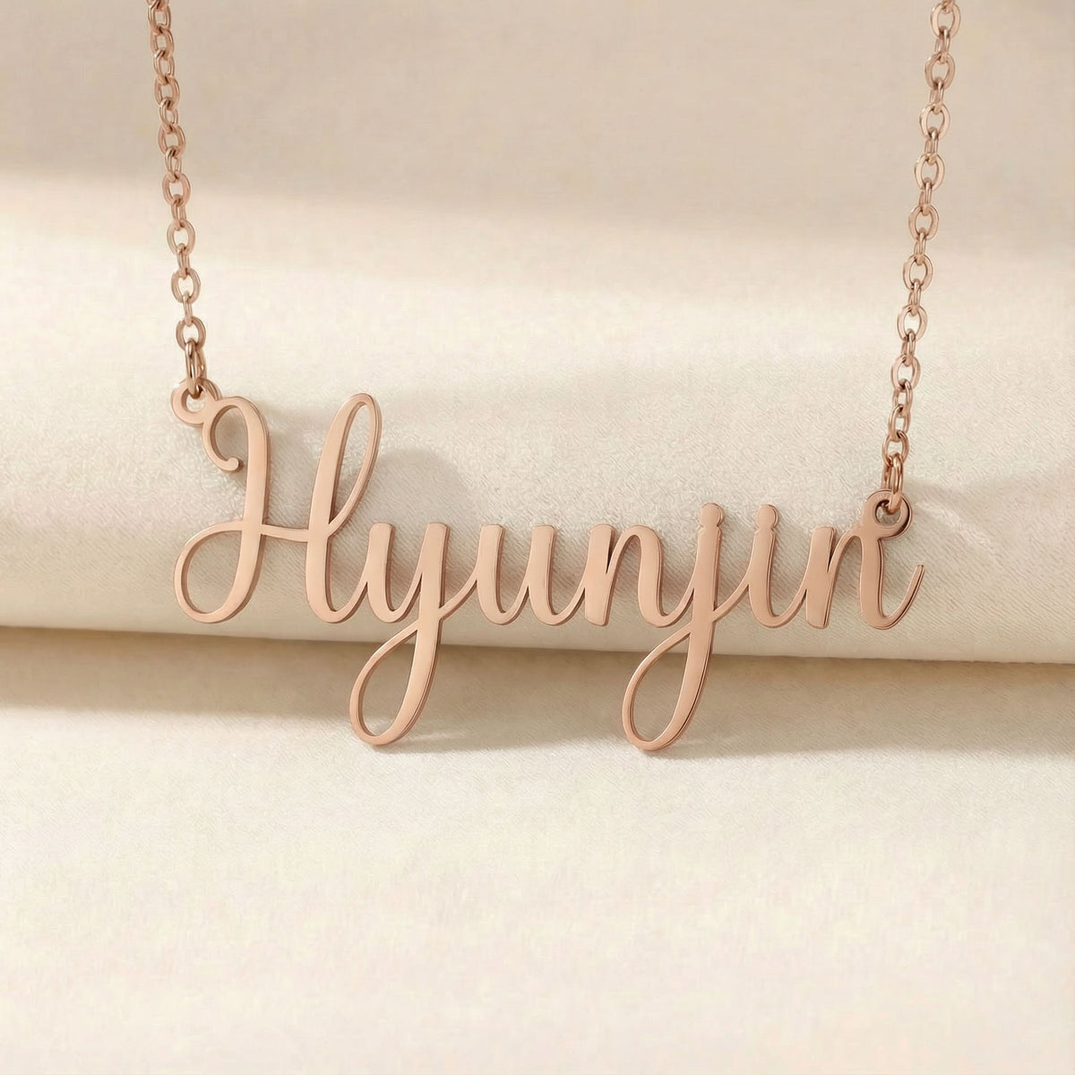 Personalized name necklace in rose gold finish on beige silk fabric