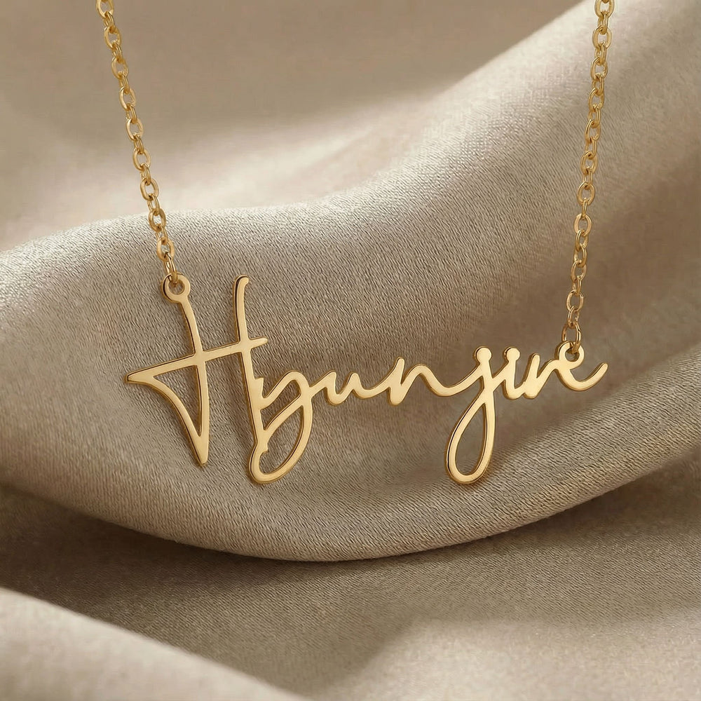 Personalized name necklace in gold finish on beige silk fabric