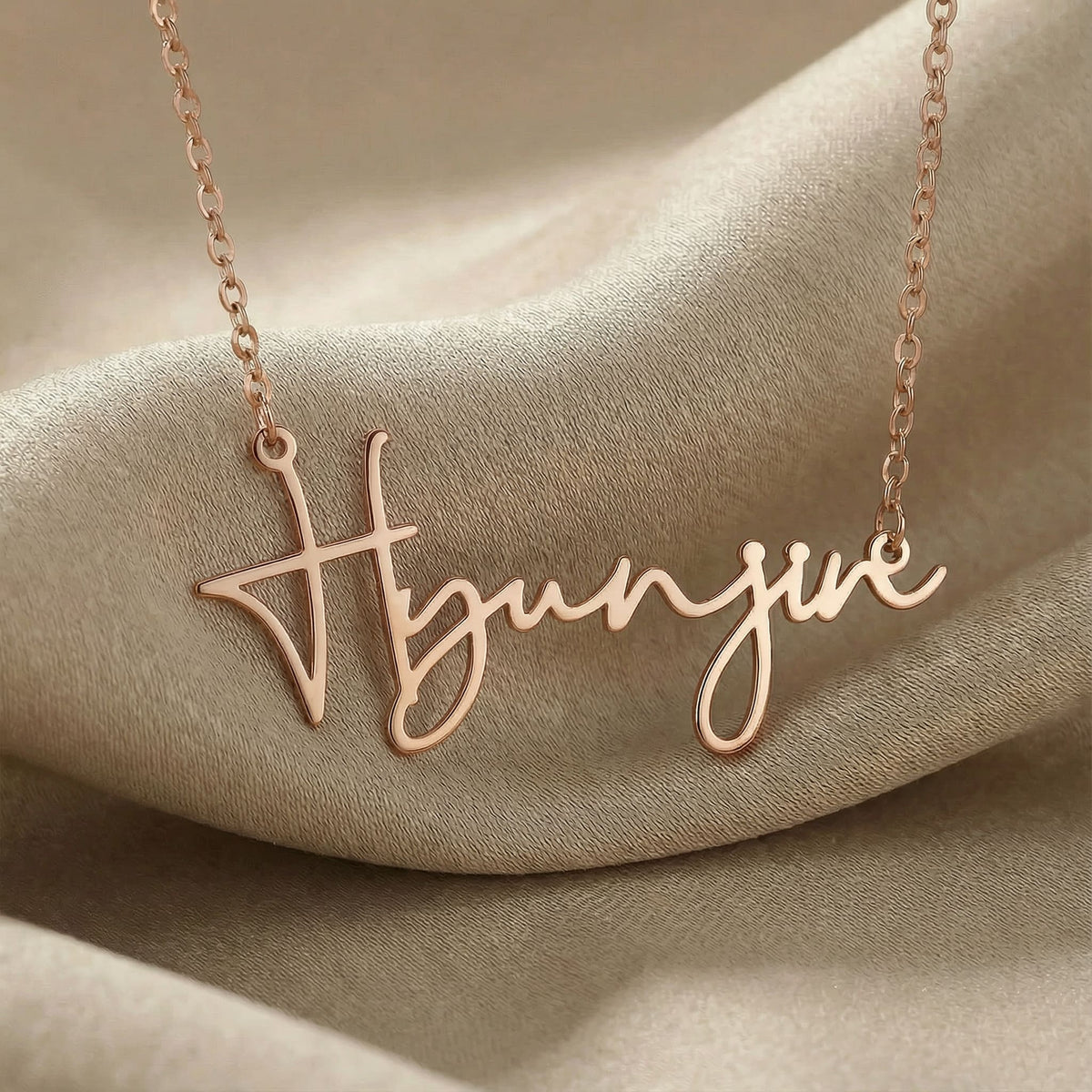Personalized name necklace in rose gold finish on beige silk fabric