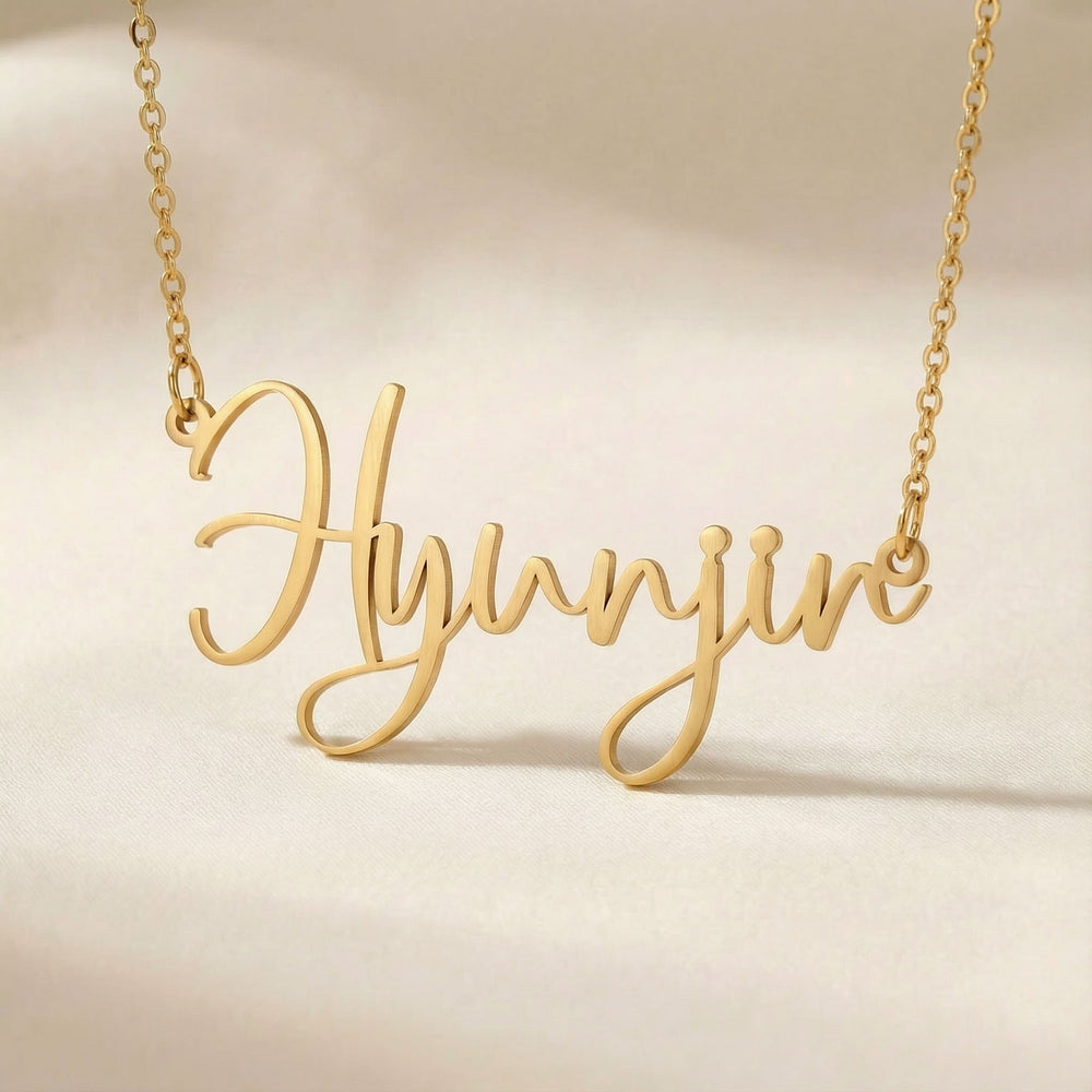 Personalized name necklace in gold finish on beige silk fabric