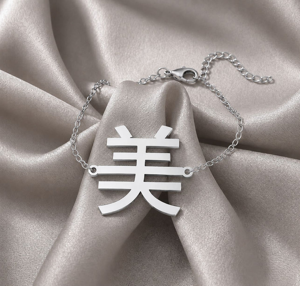 Silver necklace with a Kanji pendant meaning "beauty" on a beige fabric background