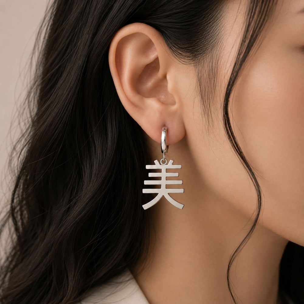 Silver earring with a Kanji character meaning "beauty" worn by a person with long dark hair.