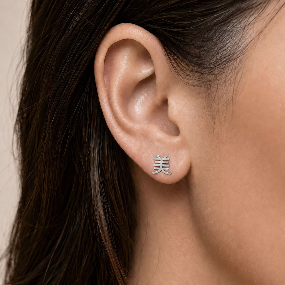Silver ear climber earring with a kanji symbol meaning "beauty" worn by an person